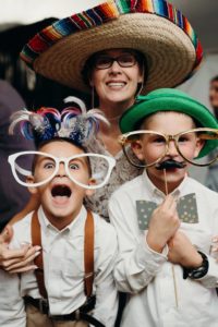 The mother and little brothers of the bride have fun with photo booth props